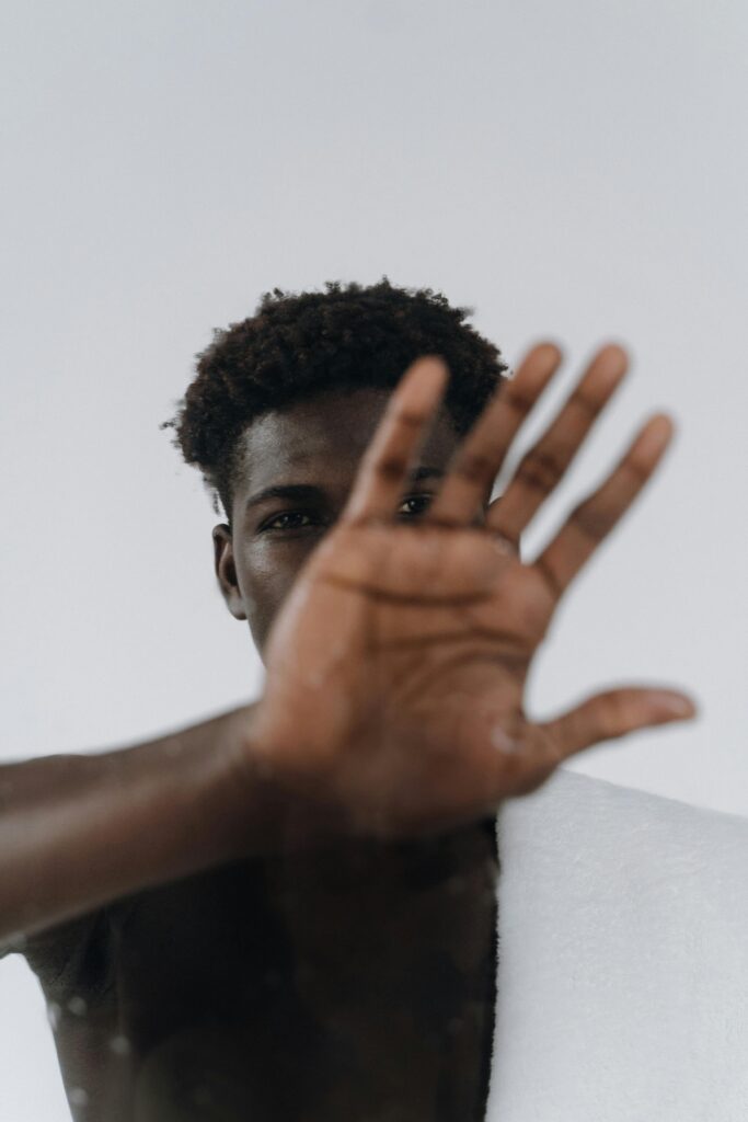 Shirtless young man reaching out with hand in front, creating depth.
